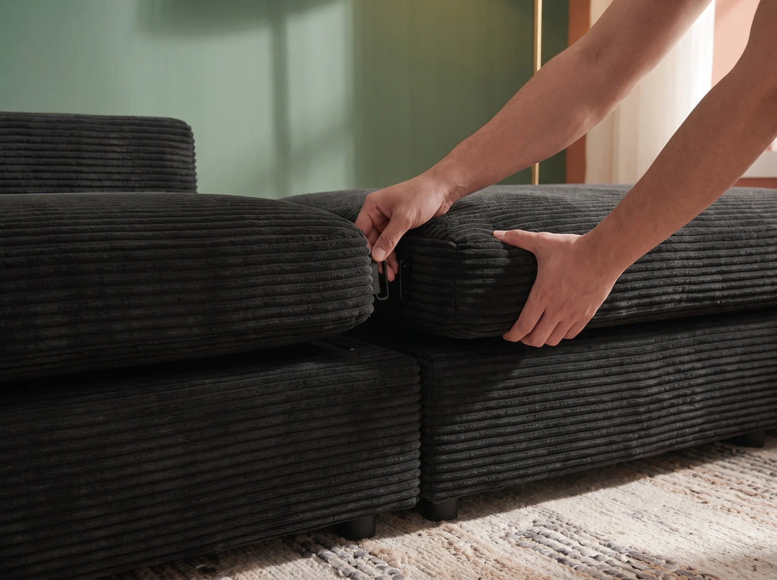 Deux mains emboîtent un module de canapé en velours côtelé noir